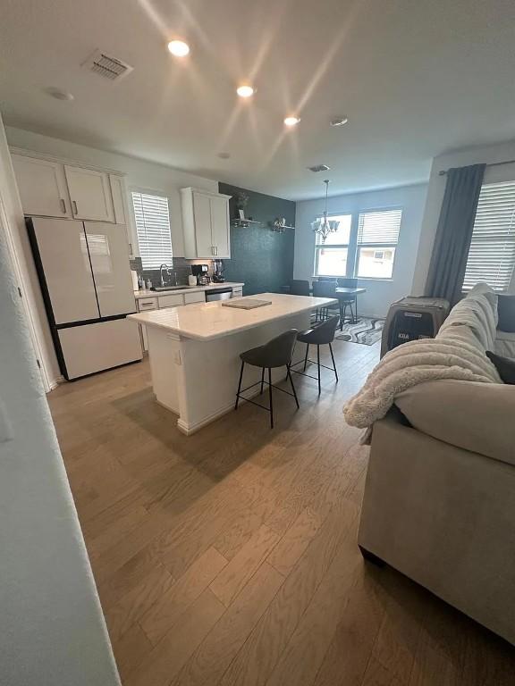 2050 Egret Ave, New Braunfels, TX 78132 - kitchen featuring freestanding refrigerator, a sink, light wood finished floors, white cabinetry, and a kitchen island