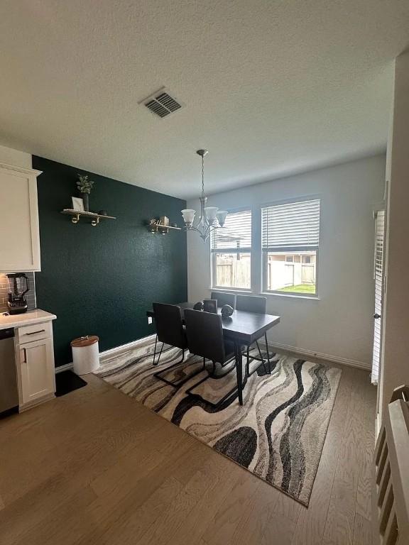 2050 Egret Ave, New Braunfels, TX 78132 - dining area featuring light wood finished floors, a chandelier, a textured ceiling, and baseboards