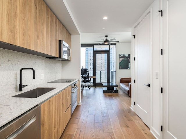 kitchen with modern cabinets, a sink, stainless steel appliances, light wood-type flooring, and recessed lighting