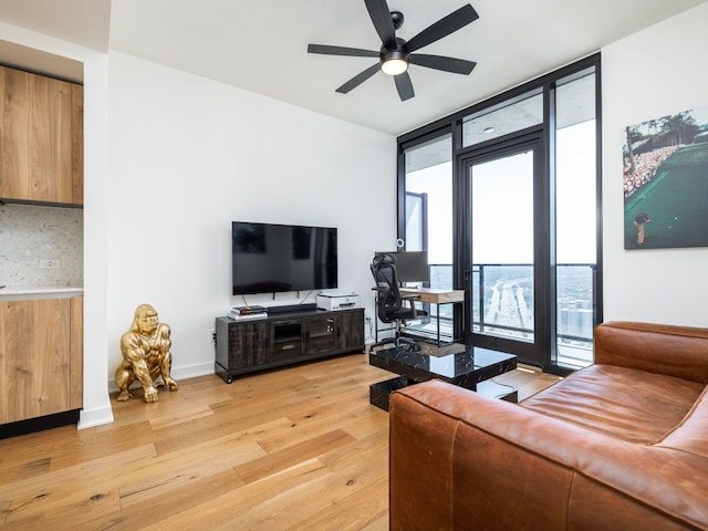 living area featuring floor to ceiling windows, light wood-style floors, and a ceiling fan