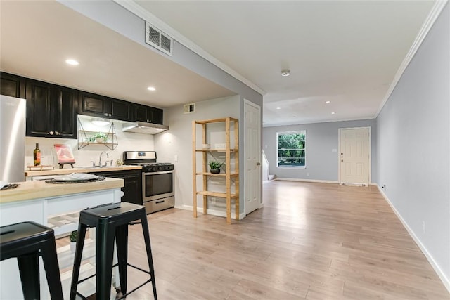 1912 Lightsey Rd Unit 1, Austin, TX 78704 - kitchen with stainless steel range with gas cooktop, under cabinet range hood, ornamental molding, light countertops, and light wood-style flooring