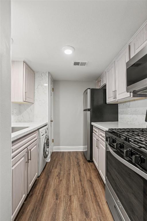 7920 Rockwood Ln Unit 104, Austin, TX 78757 - kitchen with appliances with stainless steel finishes, washer / dryer, tasteful backsplash, and light countertops