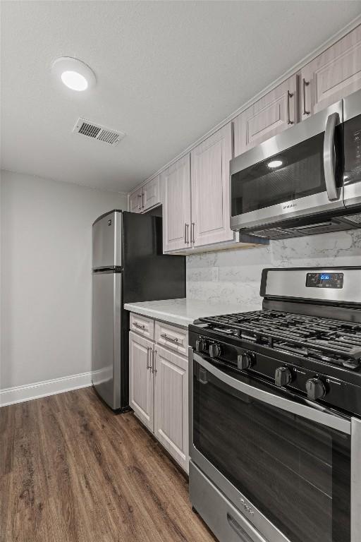 7920 Rockwood Ln Unit 104, Austin, TX 78757 - kitchen with stainless steel appliances, light countertops, dark wood finished floors, and baseboards