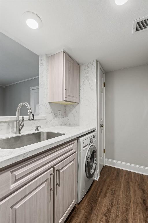 7920 Rockwood Ln Unit 104, Austin, TX 78757 - washroom with washer / dryer, cabinet space, dark wood finished floors, and baseboards