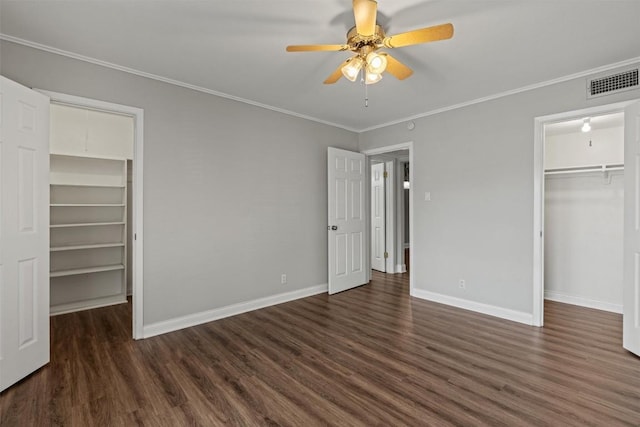 7920 Rockwood Ln Unit 104, Austin, TX 78757 - unfurnished bedroom featuring a walk in closet, dark wood-style flooring, baseboards, and ornamental molding