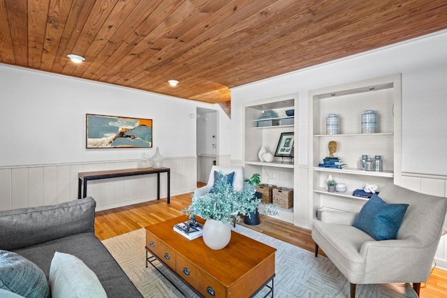 living area with wood ceiling, a wainscoted wall, built in features, and wood finished floors