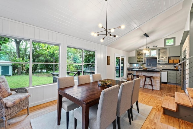 dining space featuring light wood-style floors, vaulted ceiling, and a chandelier