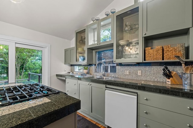 kitchen featuring a sink, dishwasher, tile counters, backsplash, and glass insert cabinets
