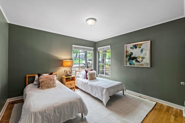 bedroom with baseboards, wood finished floors, and ornamental molding
