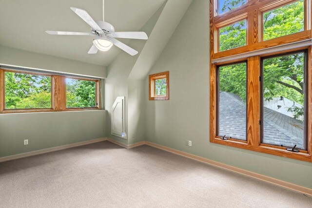 carpeted empty room featuring baseboards, vaulted ceiling, and a ceiling fan