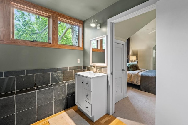 bathroom featuring tile walls, ensuite bath, vanity, and wood finished floors