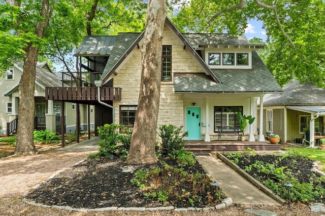 view of front of property featuring a porch, a shingled roof, and stone siding