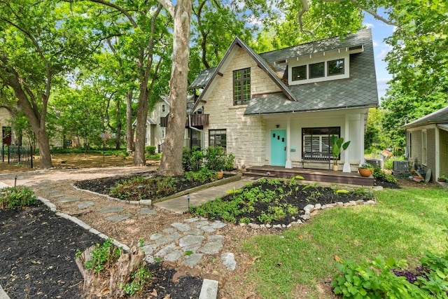 view of front of home featuring a porch, stone siding, and central AC