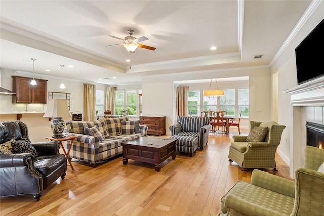 419 Davis Mountain Cir, Georgetown, TX 78633 - living room featuring a raised ceiling, plenty of natural light, light wood-type flooring, a ceiling fan, and ornamental molding