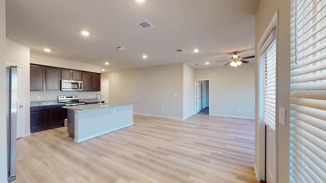 kitchen with appliances with stainless steel finishes, a sink, open floor plan, recessed lighting, and dark brown cabinets