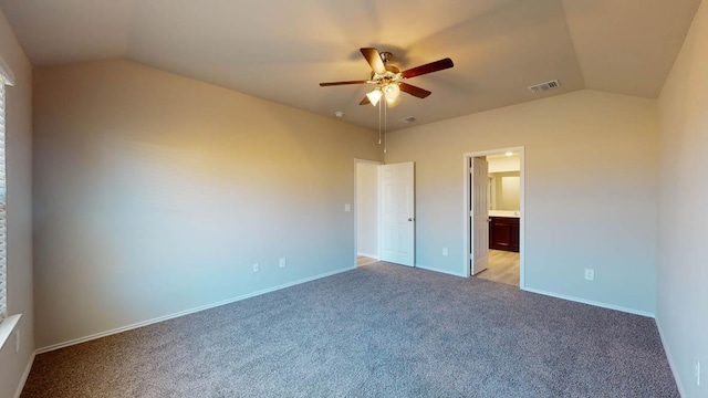 unfurnished bedroom featuring vaulted ceiling, light colored carpet, ensuite bathroom, baseboards, and a ceiling fan