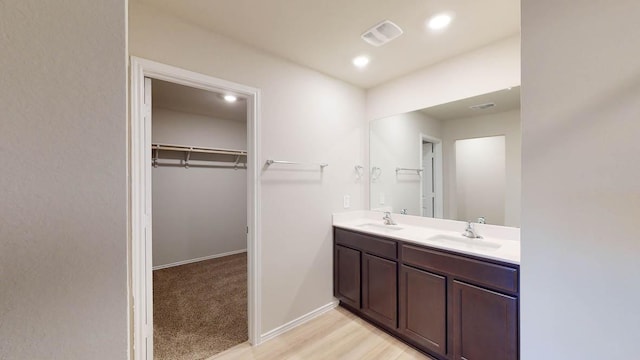 full bath featuring double vanity, a spacious closet, recessed lighting, and baseboards