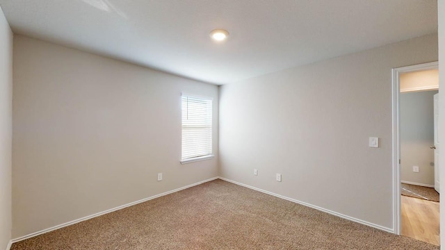 unfurnished room featuring light carpet and baseboards