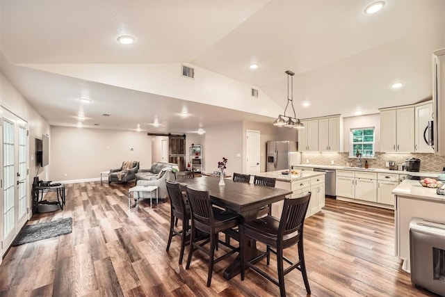 100 Comanche Trl, Georgetown, TX 78633 - dining space featuring a barn door, lofted ceiling, wood finished floors, recessed lighting, and baseboards