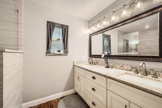 100 Comanche Trl, Georgetown, TX 78633 - bathroom featuring double vanity, baseboards, wood finished floors, a textured wall, and a textured ceiling
