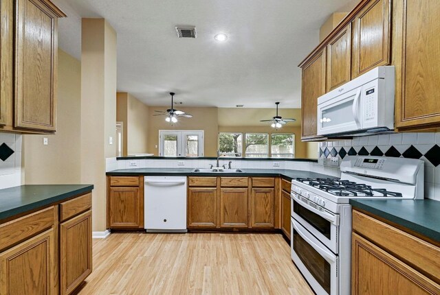 2713 Oakwood Glen Dr, Cedar Park, TX 78613 - kitchen with white appliances, a sink, dark countertops, and light wood-style floors