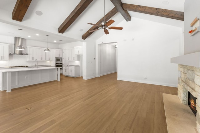 604 Germander Rd, Leander, TX 78641 - unfurnished living room with a ceiling fan, a sink, a fireplace, beam ceiling, and light wood-style floors