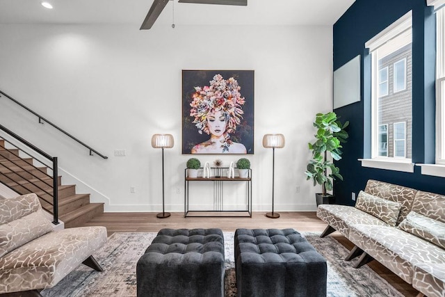 living room with wood finished floors, a ceiling fan, stairs, baseboards, and recessed lighting