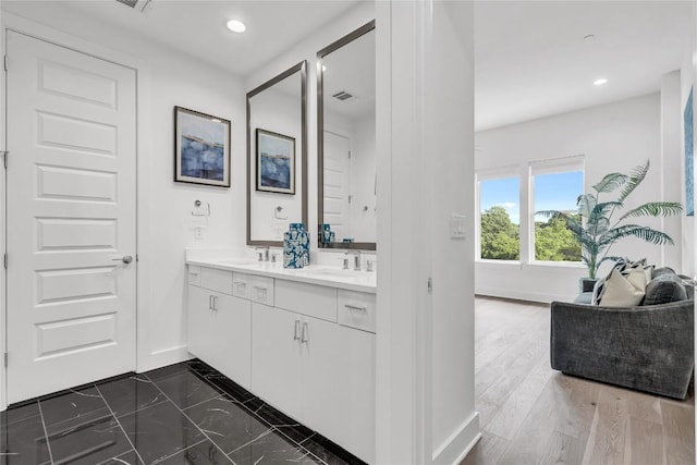 bathroom with baseboards, recessed lighting, and double vanity