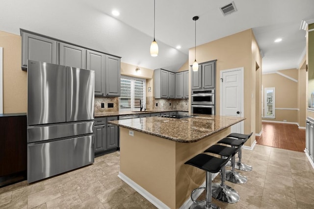 18004 Rosebud Pl, Round Rock, TX 78681 - kitchen featuring appliances with stainless steel finishes, gray cabinetry, tasteful backsplash, a sink, and a center island