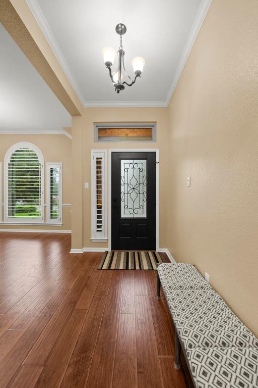 18004 Rosebud Pl, Round Rock, TX 78681 - entrance foyer featuring a chandelier, ornamental molding, wood finished floors, and baseboards