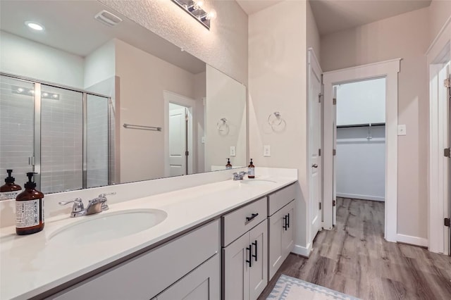 17301 Leafroller Dr Unit A, Pflugerville, TX 78660 - full bath featuring a stall shower, wood finished floors, double vanity, a walk in closet, and baseboards
