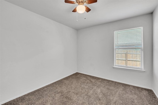 spare room featuring dark carpet, ceiling fan, and baseboards
