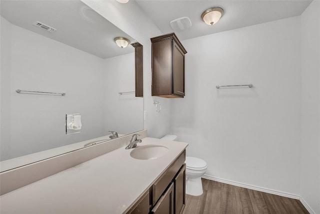half bath featuring wood finished floors, toilet, baseboards, and vanity