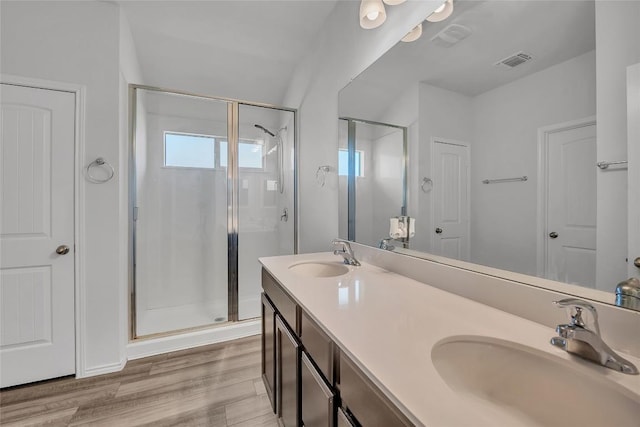 bathroom with a stall shower, wood finished floors, and double vanity