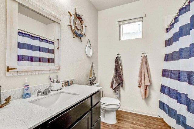 full bathroom with wood finished floors, toilet, vanity, baseboards, and a shower with curtain