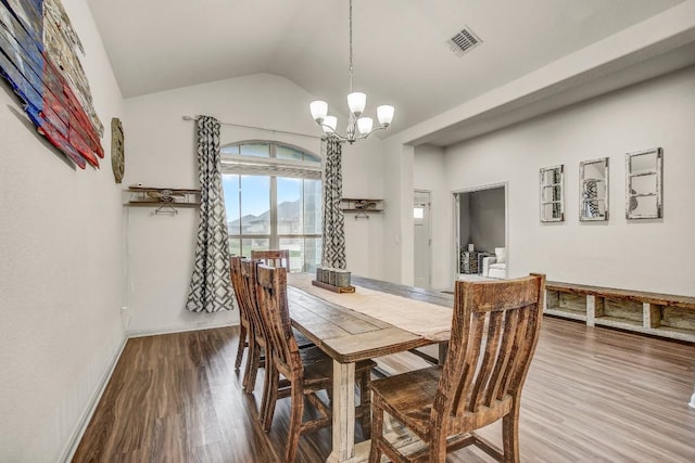 dining space with a chandelier, wood finished floors, lofted ceiling, and baseboards