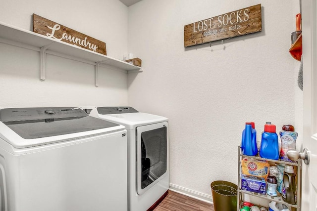 washroom featuring washing machine and clothes dryer, baseboards, and wood finished floors