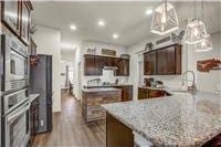 kitchen featuring oven, dark brown cabinets, wood finished floors, a peninsula, and recessed lighting