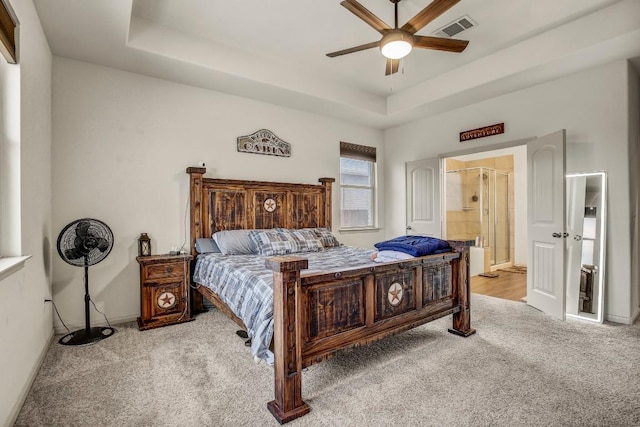 bedroom featuring carpet, a tray ceiling, connected bathroom, a ceiling fan, and baseboards