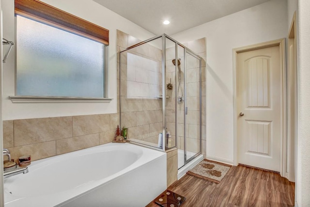 bathroom with a shower stall, wood finished floors, and a bath