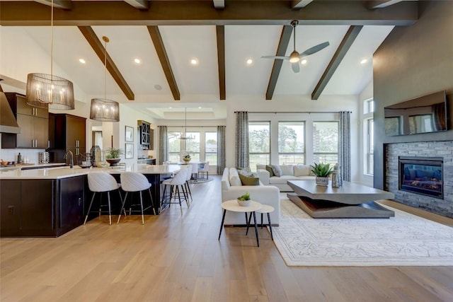 105 Isaac White Dr, Bastrop, TX 78602 - living room with high vaulted ceiling, light wood finished floors, beamed ceiling, a ceiling fan, and a stone fireplace