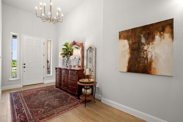 147 Epoch Dr, Austin, TX 78737 - entryway featuring a towering ceiling, a chandelier, baseboards, and wood finished floors