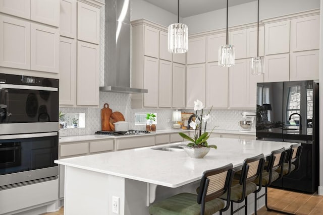 147 Epoch Dr, Austin, TX 78737 - kitchen with stainless steel double oven, wall chimney range hood, gas stovetop, light countertops, and decorative backsplash