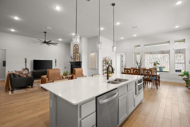 147 Epoch Dr, Austin, TX 78737 - kitchen featuring a sink, stainless steel dishwasher, light wood finished floors, a center island with sink, and light countertops