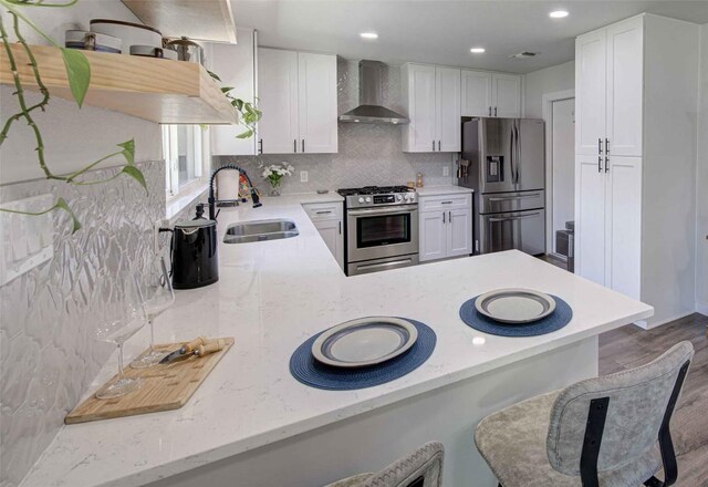 10500 Berthound Dr, Austin, TX 78758 - kitchen featuring stainless steel appliances, wall chimney exhaust hood, a sink, backsplash, and wood finished floors