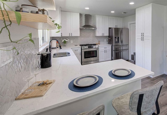 10500 Berthound Dr, Austin, TX 78758 - kitchen with appliances with stainless steel finishes, wall chimney exhaust hood, backsplash, wood finished floors, and white cabinets