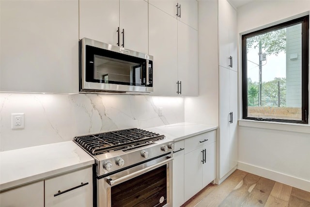 3208 Clawson Rd Unit 2, Austin, TX 78704 - kitchen featuring appliances with stainless steel finishes, backsplash, light countertops, light wood finished floors, and white cabinetry