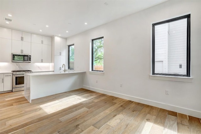3208 Clawson Rd Unit 2, Austin, TX 78704 - kitchen with appliances with stainless steel finishes, light countertops, white cabinetry, a peninsula, and recessed lighting