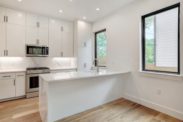 3208 Clawson Rd Unit 2, Austin, TX 78704 - kitchen with appliances with stainless steel finishes, a sink, light wood finished floors, light countertops, and white cabinetry