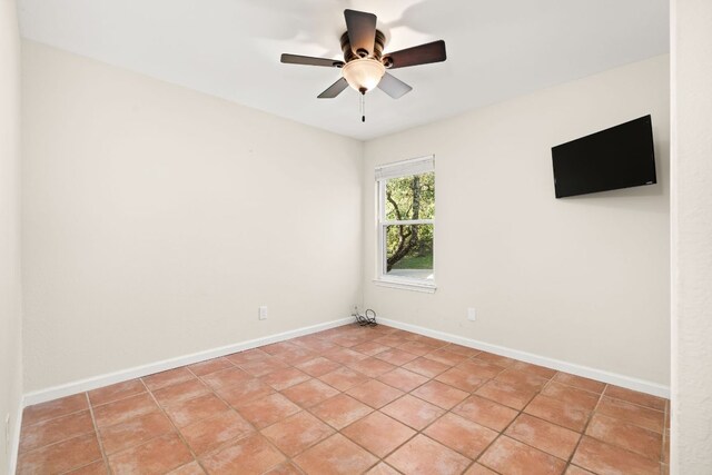 spare room featuring ceiling fan, light tile patterned floors, and baseboards